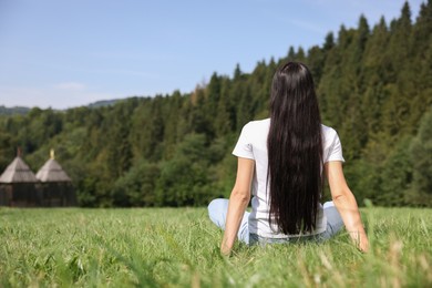 Photo of Feeling freedom. Woman enjoying nature on green grass outdoors, back view and space for text