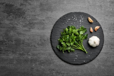 Flat lay composition with fresh parsley and garlic on grey background