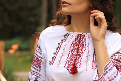 Photo of Woman in beautiful embroidered shirt outdoors, closeup. Ukrainian national clothes