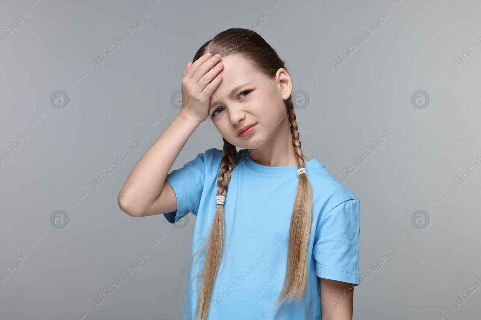 Photo of Little girl suffering from headache on grey background