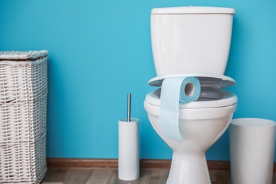 Toilet bowl with paper roll in bathroom