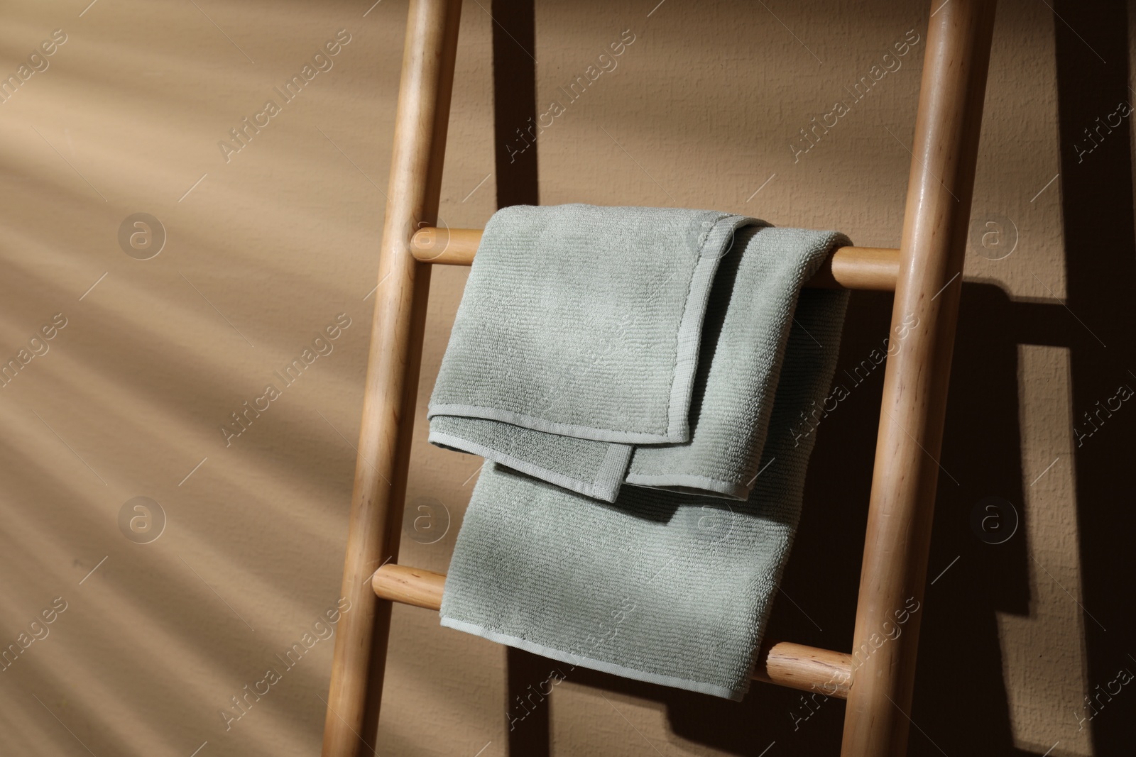 Photo of Terry towel on wooden decorative ladder near beige wall