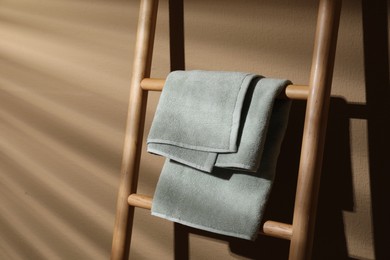 Terry towel on wooden decorative ladder near beige wall