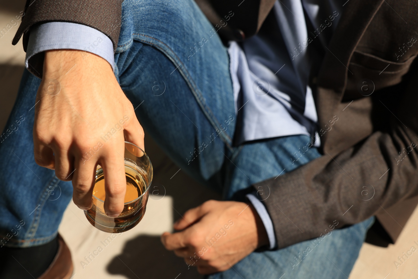 Photo of Addicted man with glass of alcoholic drink sitting on floor, closeup