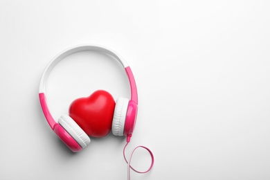 Photo of Decorative heart and modern headphones on white background, top view