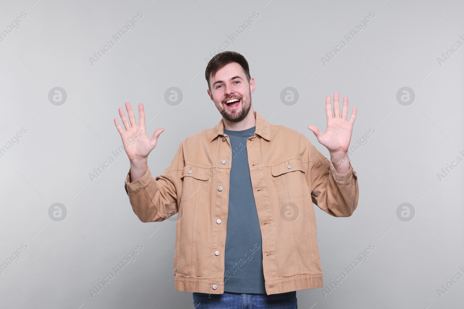 Photo of Man giving high five with both hands on grey background
