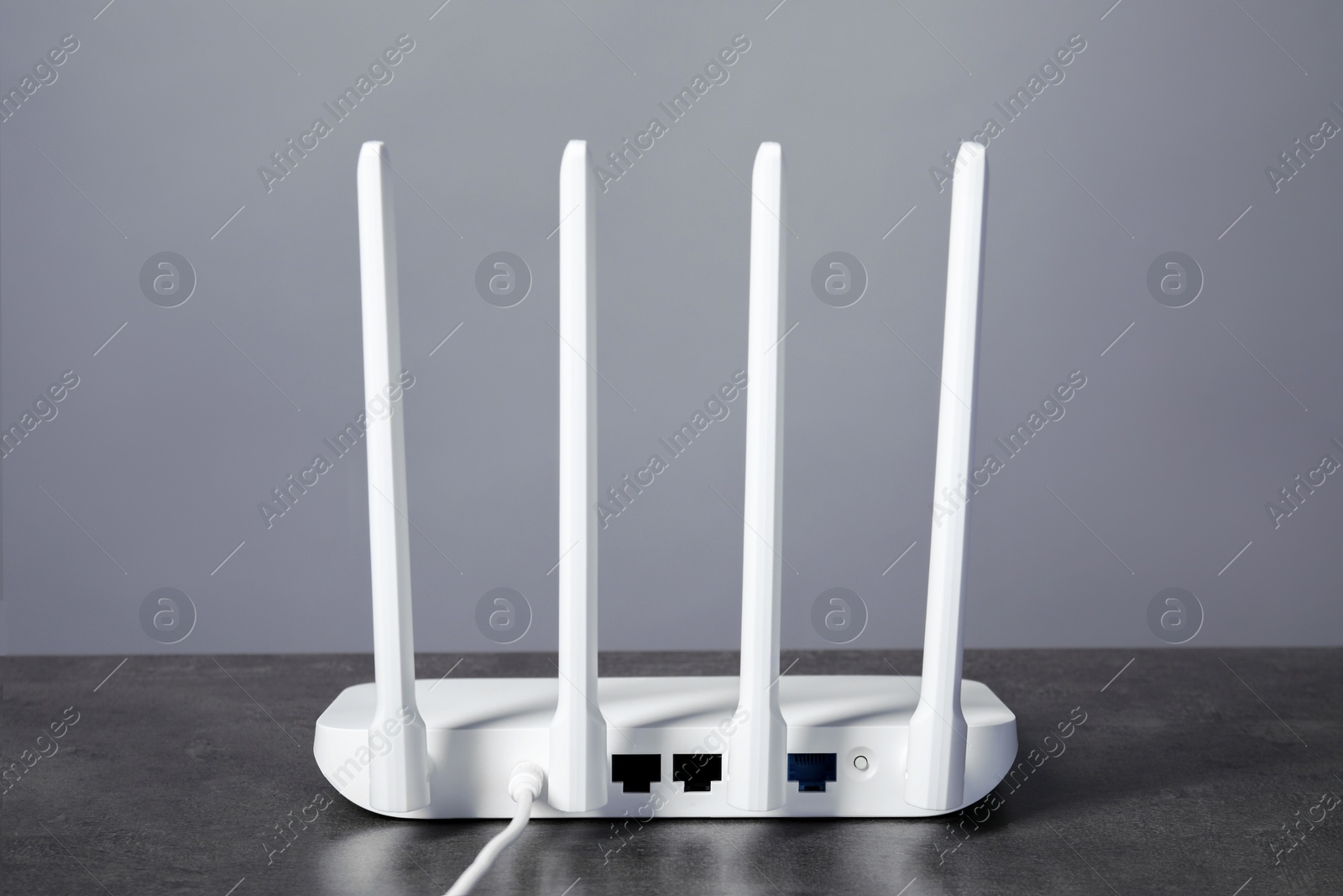 Photo of Wi-Fi router on grey textured table, back view