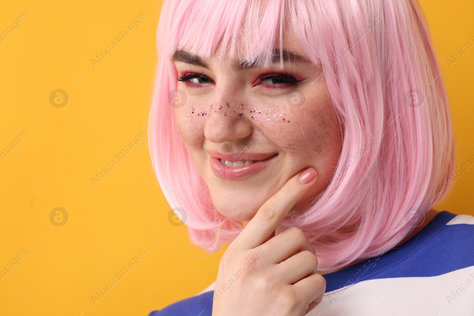 Photo of Beautiful woman with bright makeup and glitter freckles on yellow background, closeup. Space for text