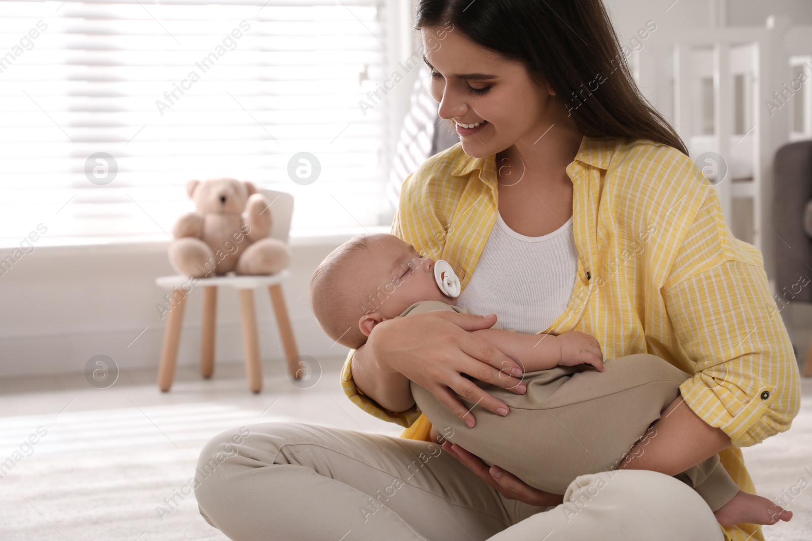 Photo of Young woman with her sleeping baby on floor at home