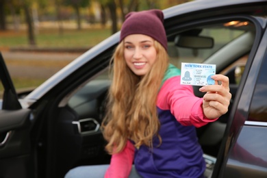 Photo of Happy woman holding driving license in car. Space for text