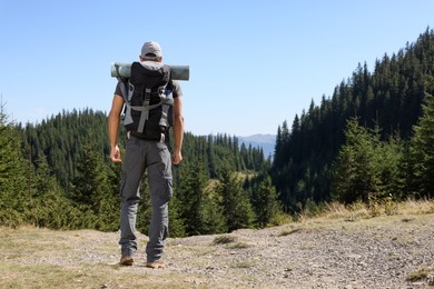 Photo of Tourist with backpack in mountains on sunny day, back view. Space for text