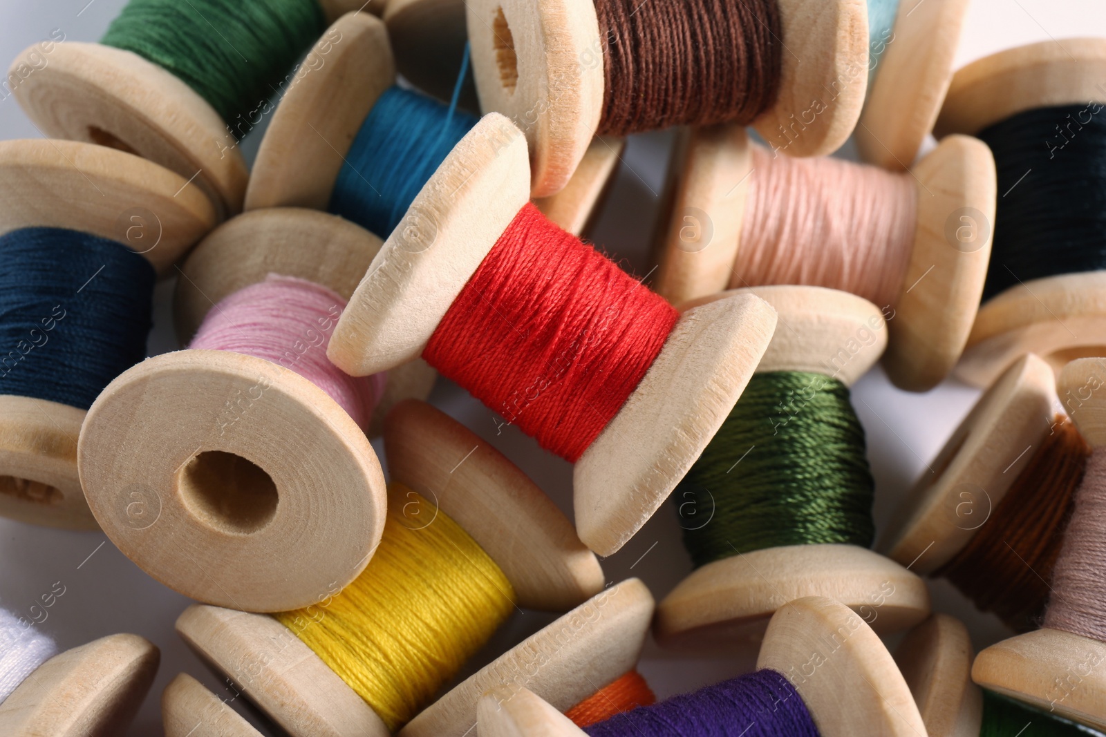 Photo of Pile of wooden spools with colorful sewing threads, closeup