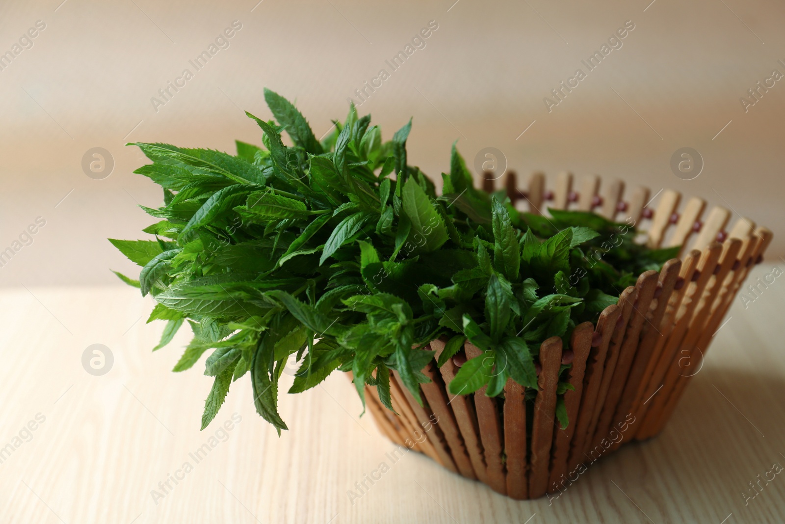 Photo of Beautiful green mint in basket on white wooden table