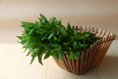 Photo of Beautiful green mint in basket on white wooden table