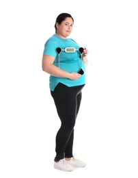 Overweight woman in sportswear with scales on white background