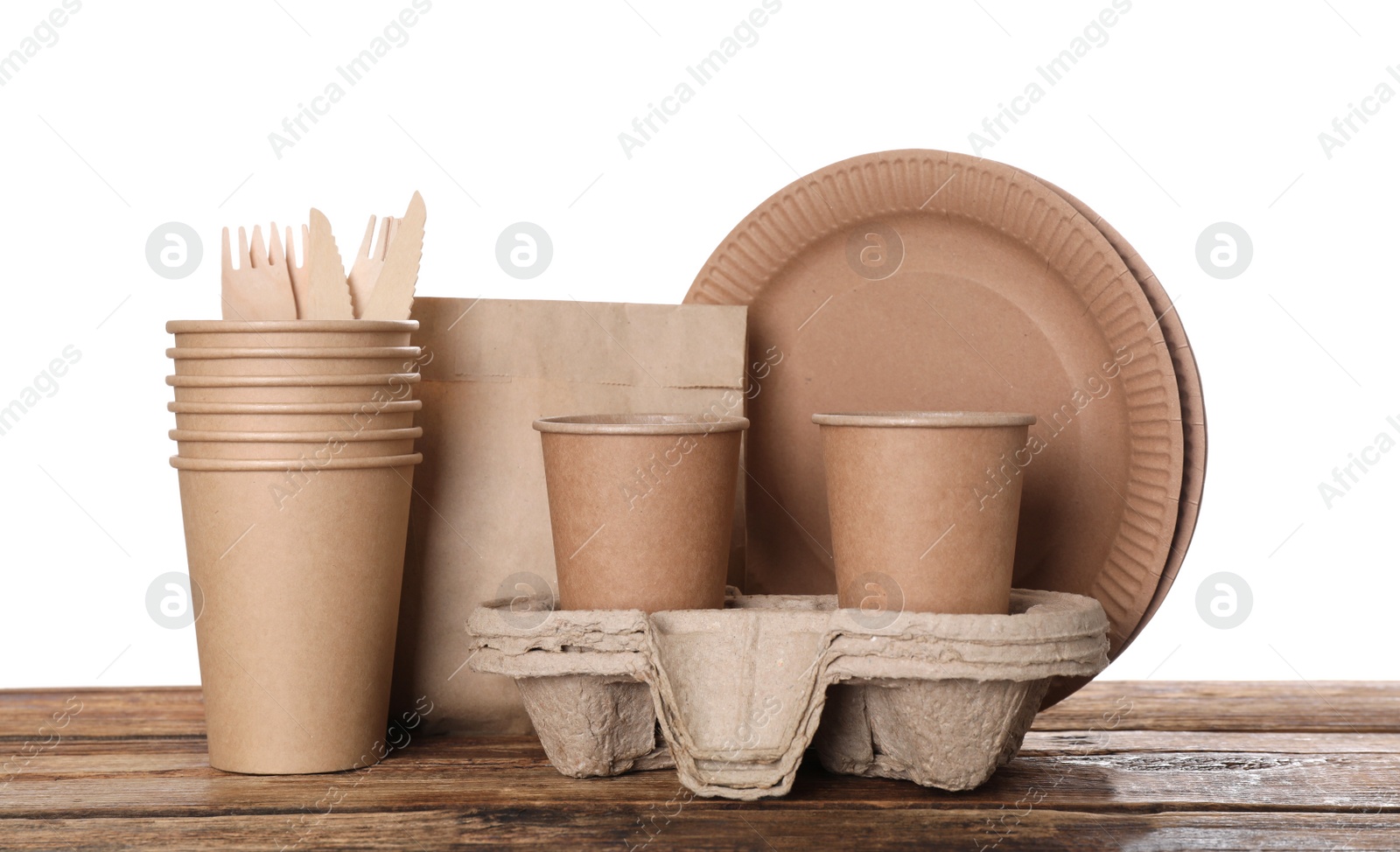 Photo of Set of disposable eco friendly dishware on wooden table against white background