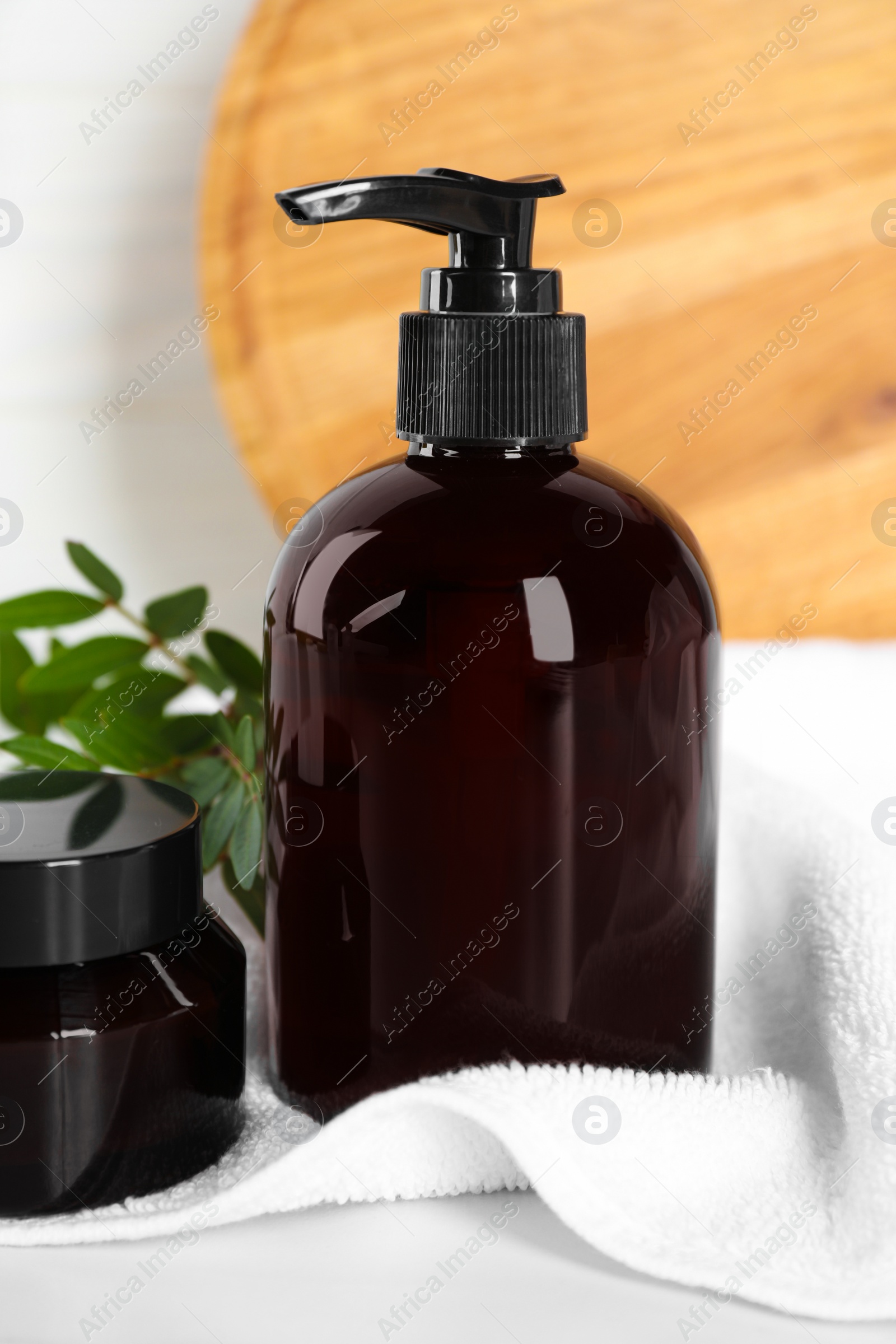 Photo of Shampoo bottle, hair mask and towel on white wooden table