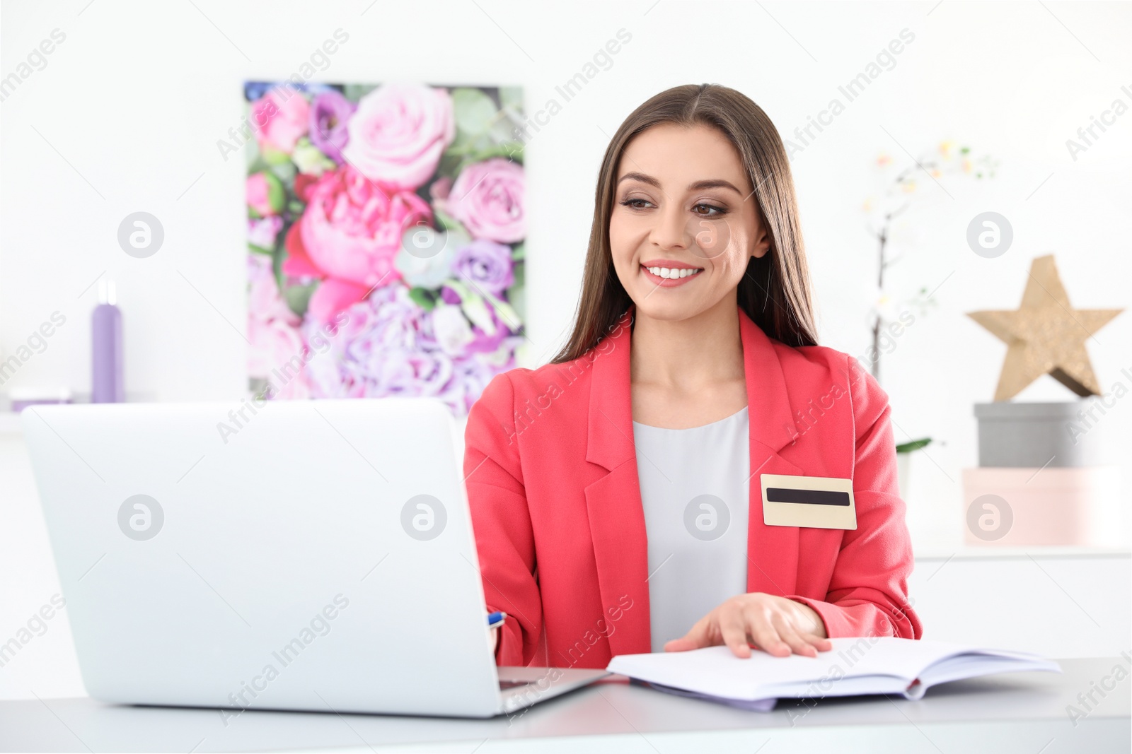 Photo of Beauty salon receptionist using laptop at desk