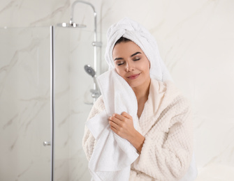 Photo of Young woman wiping face with towel in bathroom