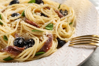 Photo of Delicious pasta with anchovies, olives and parmesan cheese on table, closeup