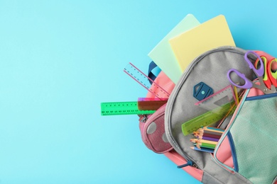 Photo of Stylish backpack with different school stationery on light blue background, top view and space for text. Back to school