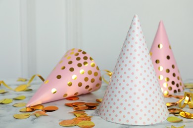 Party hats and shiny confetti on white marble table