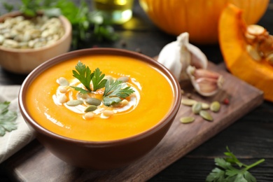 Delicious pumpkin soup in bowl on wooden table