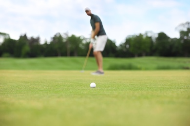 Photo of Man playing golf on green course, ball in focus