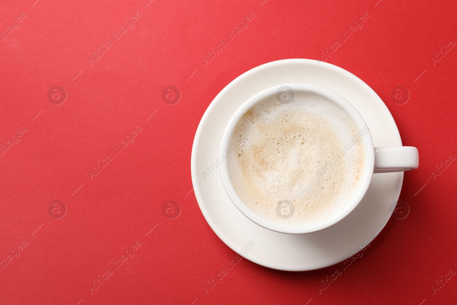 Photo of Cup of aromatic coffee on red background, top view. Space for text