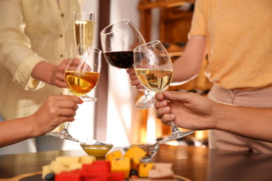 Photo of Group of friends toasting with wine at table, closeup