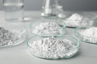 Photo of Many petri dishes with calcium carbonate powder on white table
