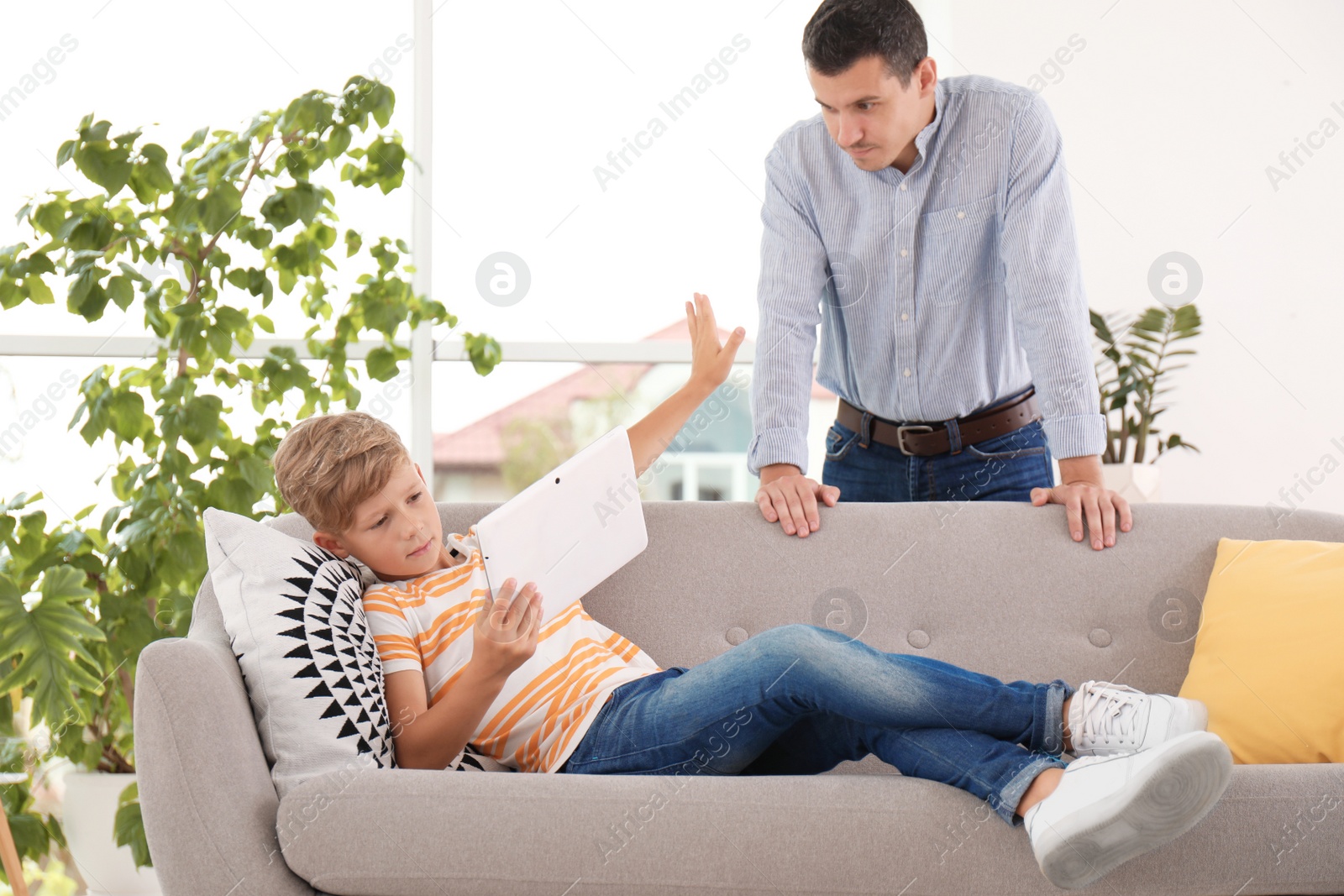 Photo of Father scolding child while he using tablet at home. Family problems