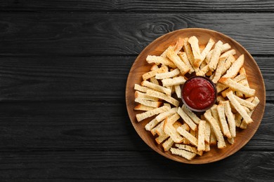 Photo of Delicious hard chucks with ketchup on black wooden table, top view. Space for text