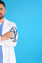 Mature doctor with stethoscope on blue background, space for text