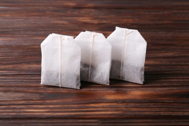 Many paper tea bags on wooden table, closeup