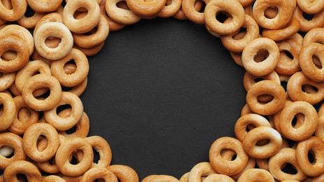 Photo of Frame made of tasty dry bagels (sushki) on black background, flat lay. Space for text