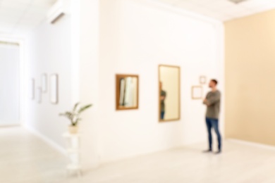 Young man in hall of modern art gallery, blurred view