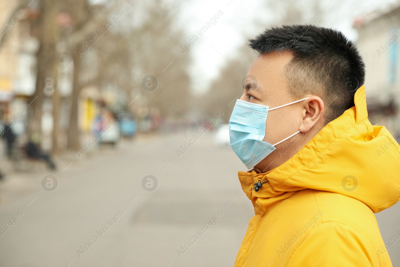 Photo of Asian man wearing medical mask on city street, space for text. Virus outbreak