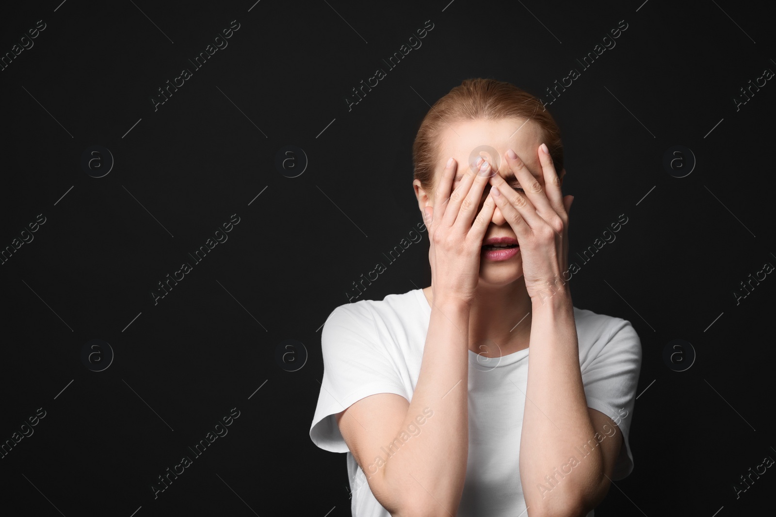 Photo of Young woman feeling fear on black background. Space for text