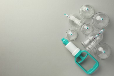 Photo of Plastic cups and hand pump on light grey background, flat lay with space for text. Cupping therapy
