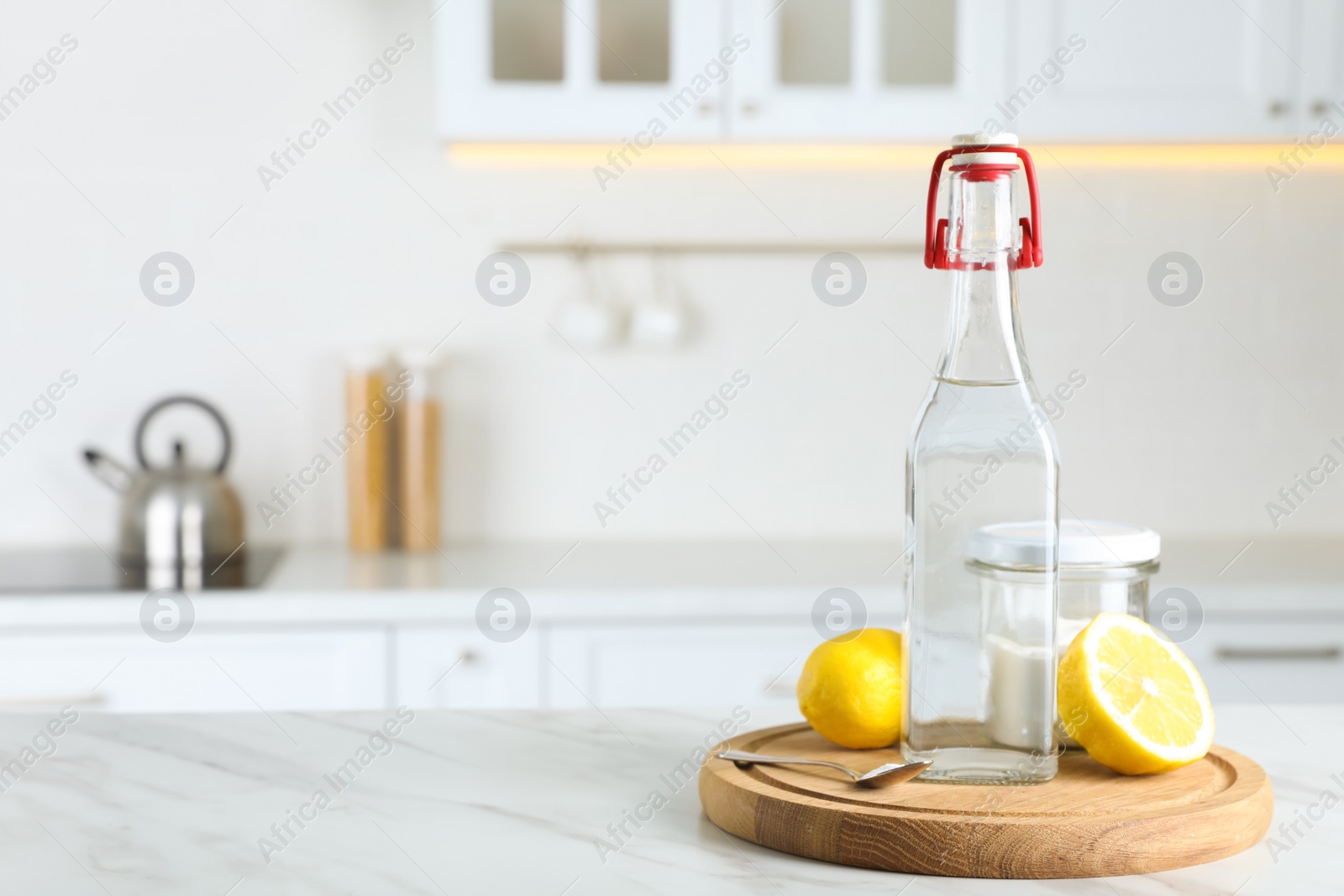 Photo of Vinegar, baking soda and lemon on white marble table in kitchen, space for text. Eco friendly natural detergents