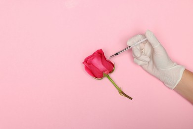 Doctor making injection to rose on pink background, top view. Space for text