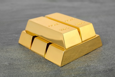 Photo of Stacked shiny gold bars on grey table