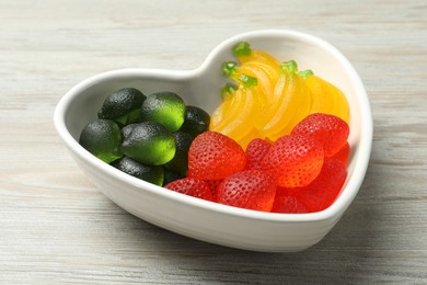 Photo of Delicious gummy fruit shaped candies on white wooden table