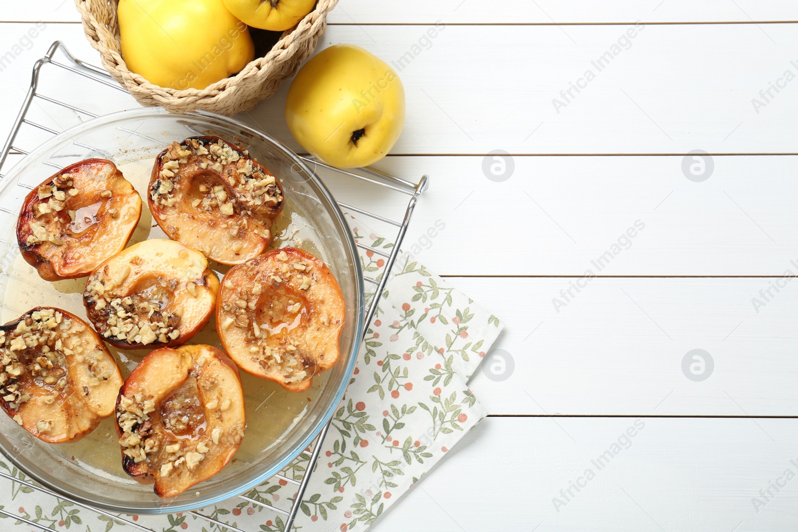 Photo of Delicious baked quinces with nuts in bowl and fresh fruits on white wooden table, flat lay. Space for text