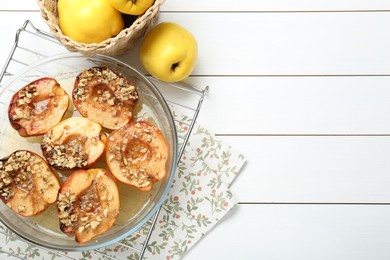 Delicious baked quinces with nuts in bowl and fresh fruits on white wooden table, flat lay. Space for text