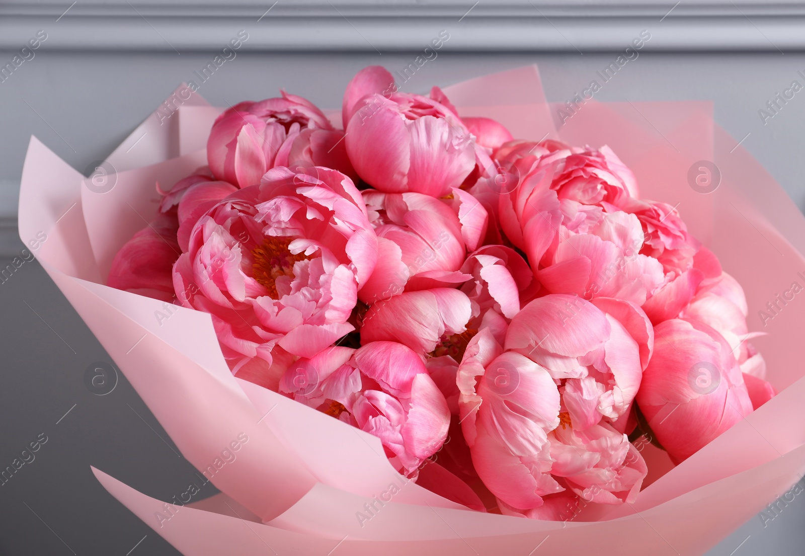 Photo of Bouquet of beautiful pink peonies near grey wall, closeup