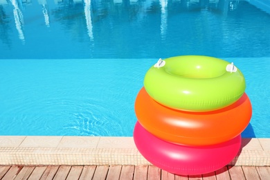 Photo of Modern swimming pool with inflatable rings outdoors. Space for text