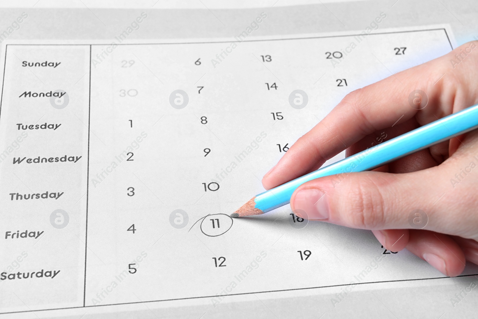 Photo of Woman marking date in calendar with pencil, closeup