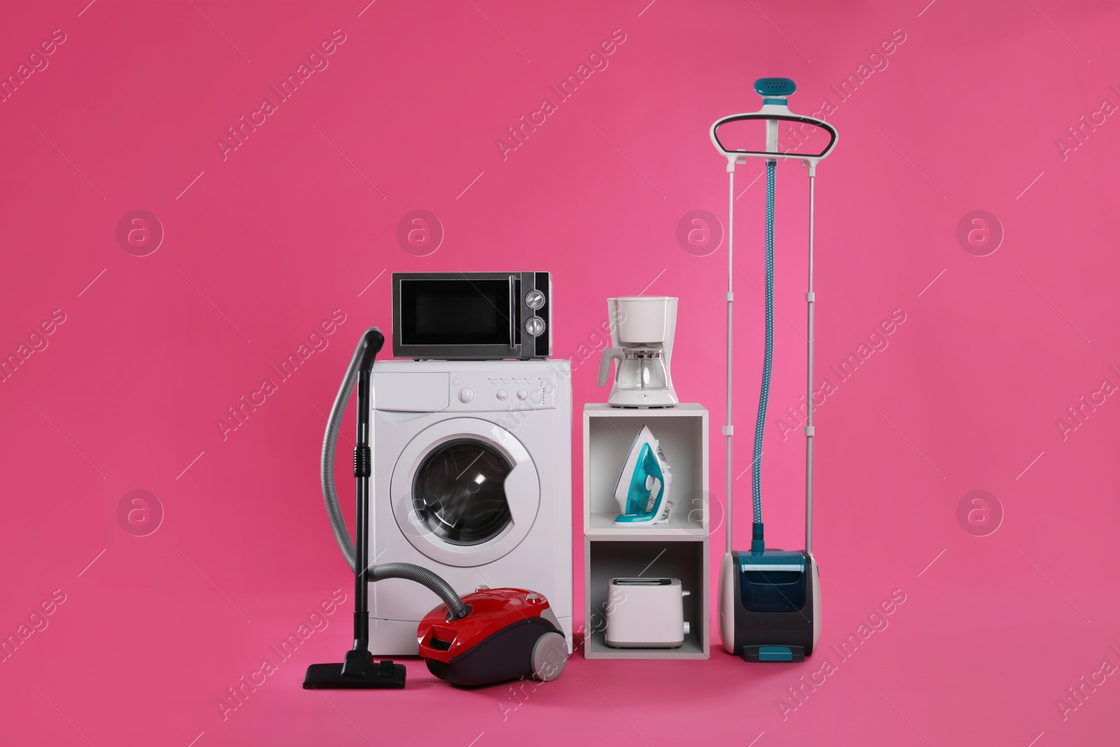 Photo of Set of different home appliances with vacuum cleaner on pink background